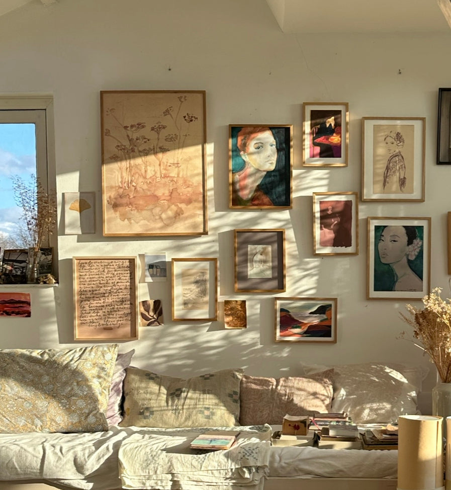 Gallery wall with framed , abstract, and figurative art prints including handwritten poetic text in bright art studio