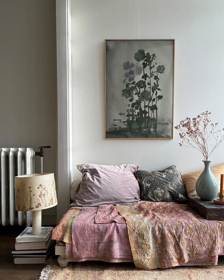 Floral-themed wall art in charcoal green/grey tones above a styled sofa with pillows, and vintage-inspired decor.