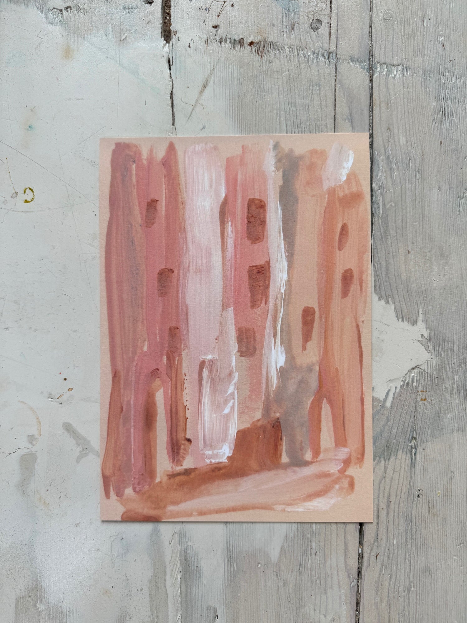 Cozy shelf with large abstract painting, small cityscape watercolor, pink candle, and pottery bowls.