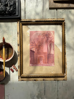 Watercolor of an architectural archway with palm trees in pink and brown tones, beside paintbrush and pastel chalks