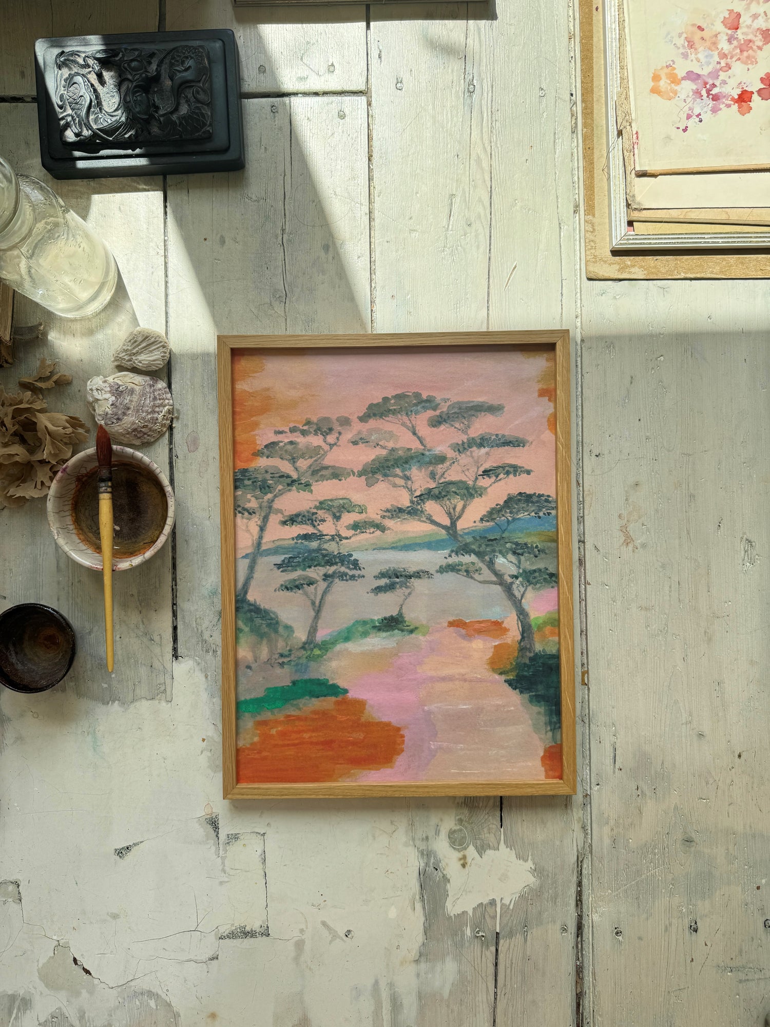 Abstract landscape painting with trees and colorful path in wooden frame on rustic wooden background.