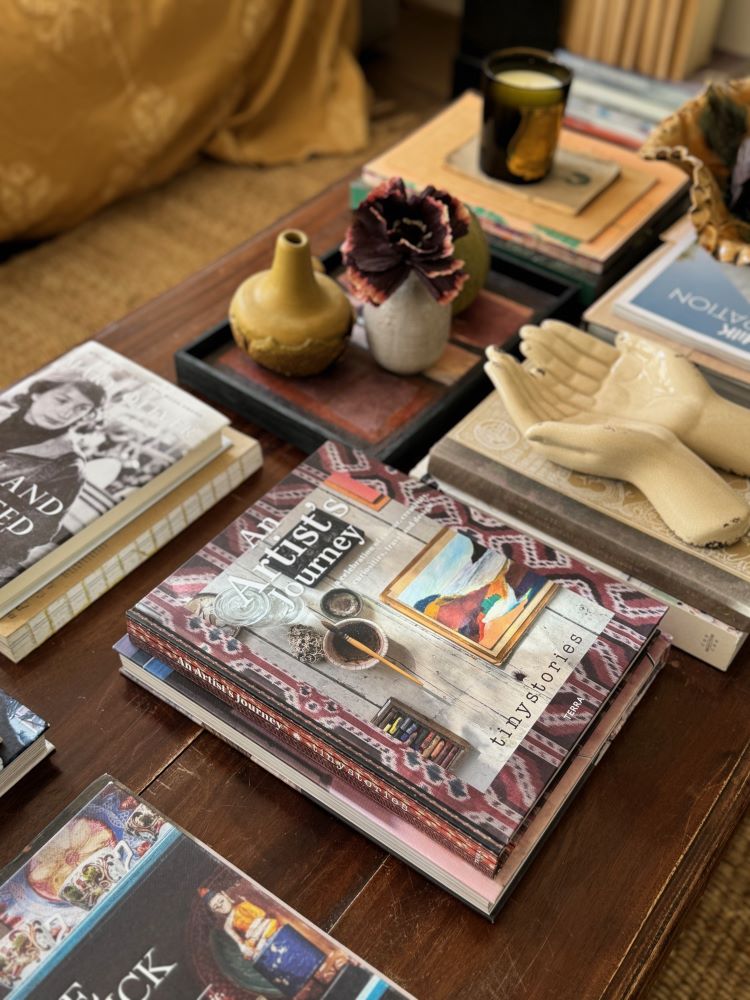 Table with various books, ceramic vases, and decorative objects including "An Artist's Journey."