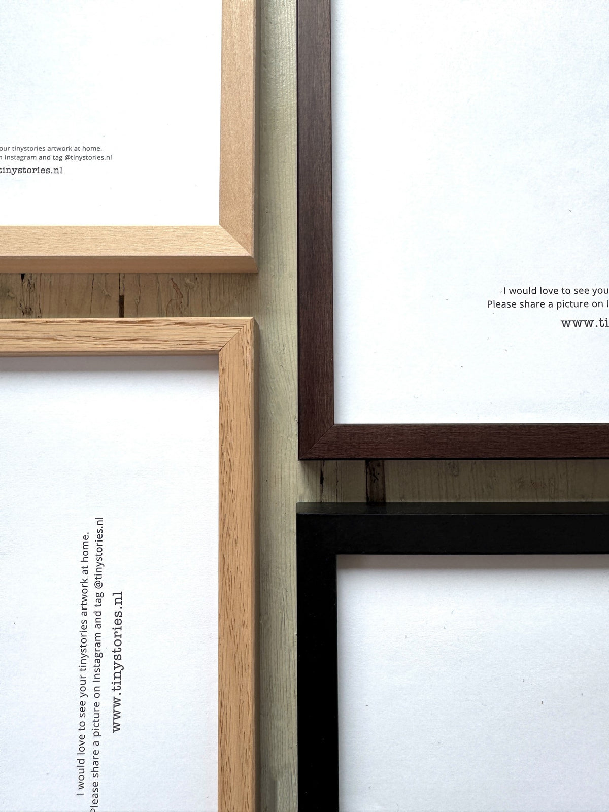 Close-up of four empty picture frames in natural wood, dark brown, black, and white colors on a wooden surface