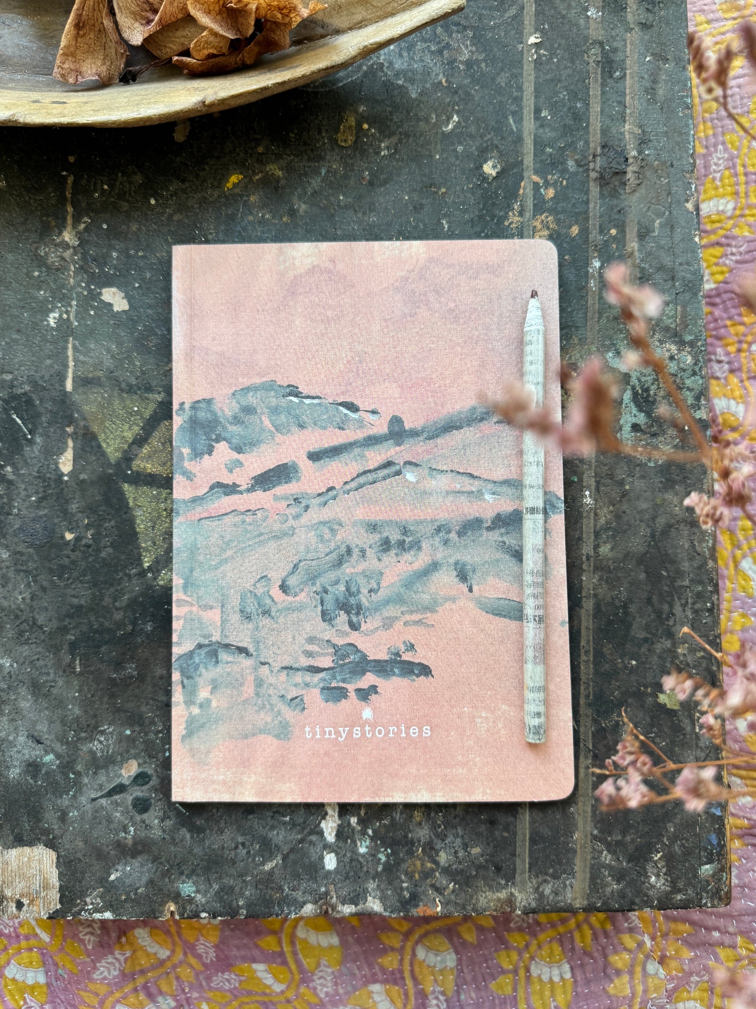 notebook in size DIN A5 showing an abstract landscape in soft colours with a pencil laying beside it